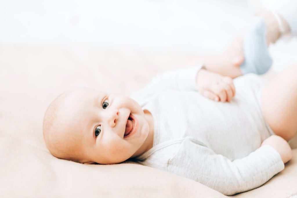 newborn laughing baby lying on the bed caring for newborn children 1024x682 1